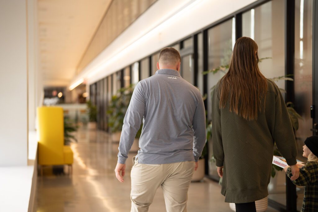 Blake Robbins, award-winning financial manager and entrepreneur, and his wife walk down a hall in the Ledger office building in Bentonville, AK, towards their financial management office there